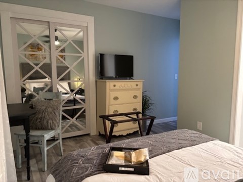 A bedroom with a bed, a chair, a dresser, and a television.