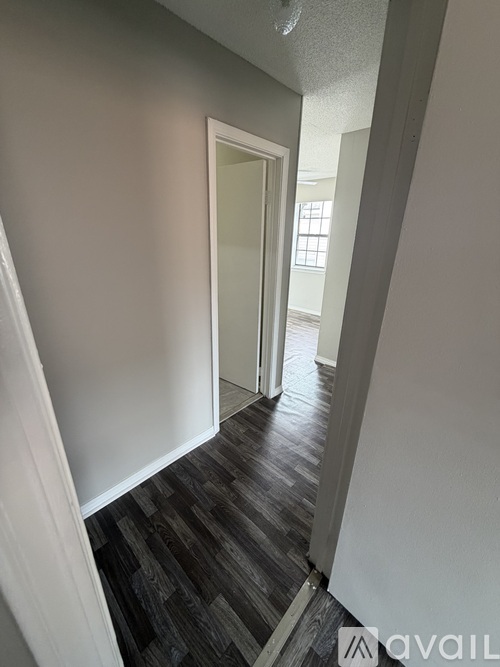 A hallway with a wooden floor and white walls.