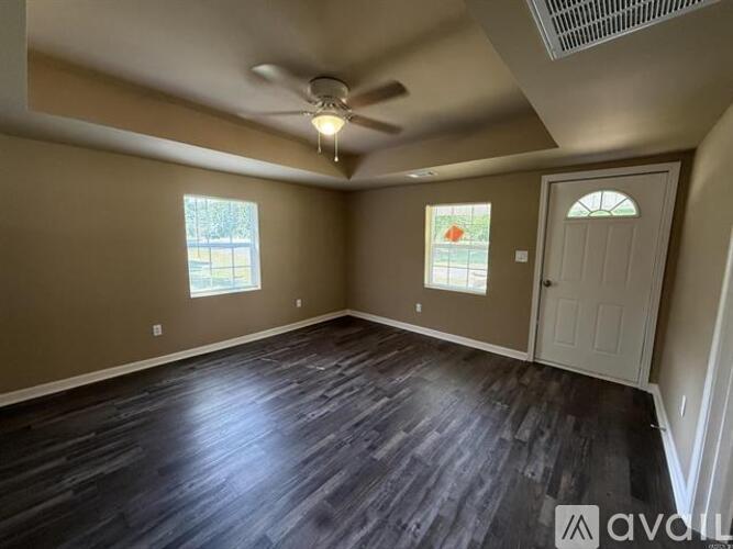 A room with a ceiling fan and two windows.