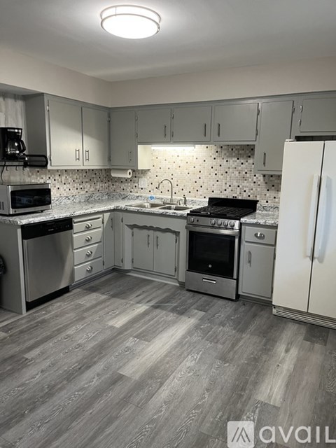 A kitchen with a white fridge, microwave, oven, and dishwasher.