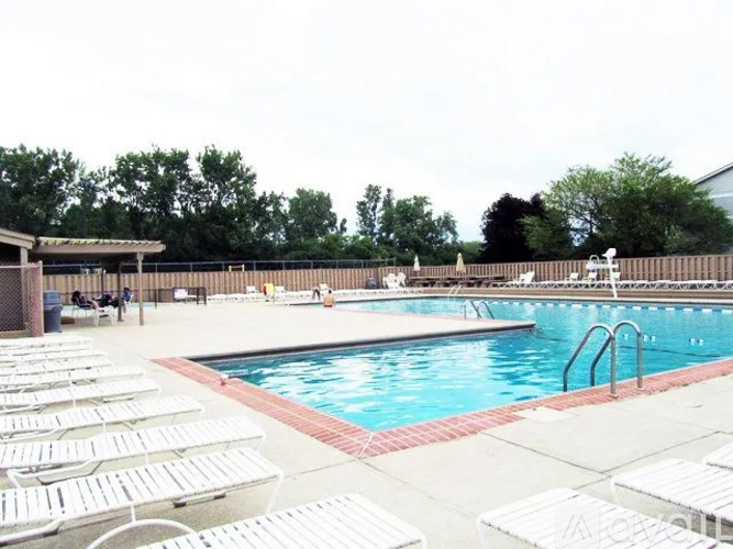 A pool with sun loungers and people in the background.