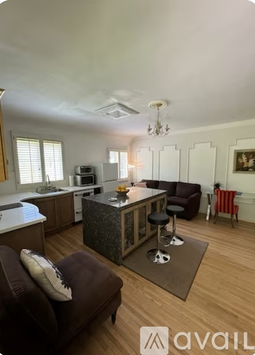 A modern kitchen with a bar stool and a sofa.