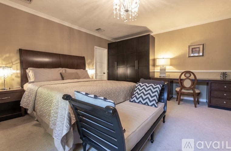 A bedroom with a large bed and a desk with a chair.