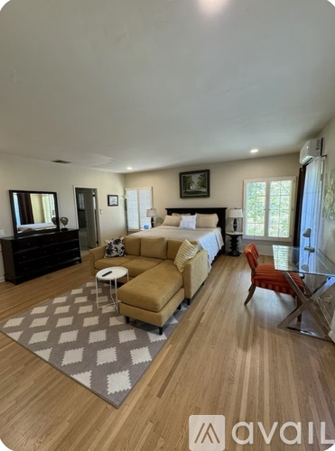 A living room with a tan couch and a grey rug.