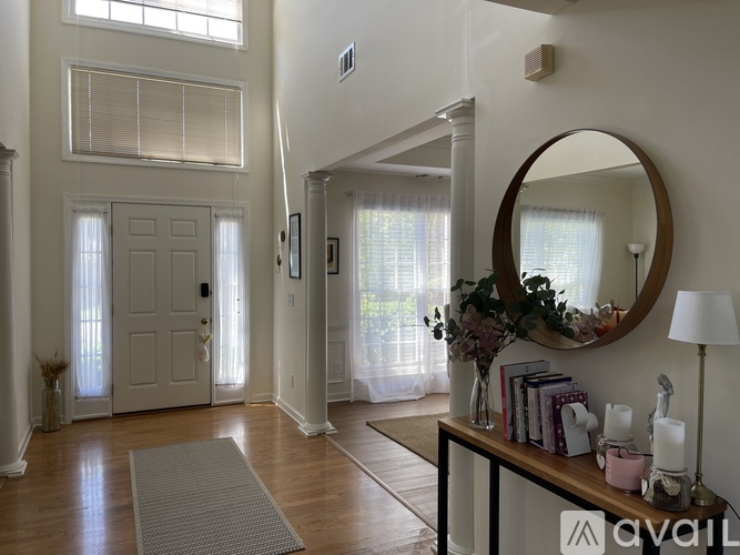 A living room with a grey rug and a round mirror on the wall.