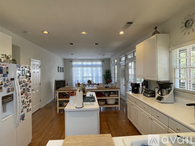 A kitchen with white cabinets and a refrigerator filled with magnets.