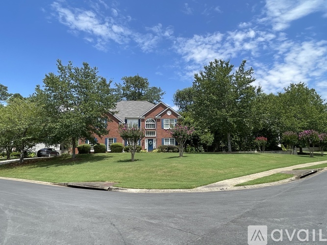 A house with a blue door is surrounded by greenery and trees.