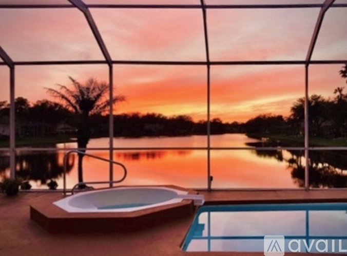 A hot tub sits on a deck overlooking a body of water during sunset.