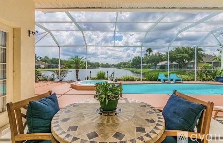 A table with a plant on it and a view of a pool through a window.
