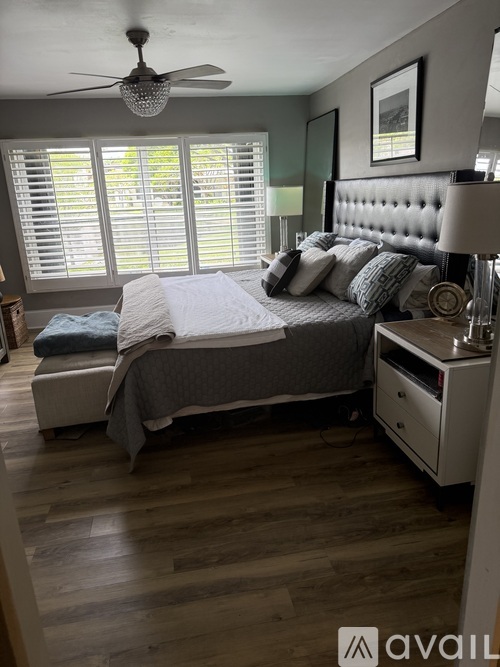 A bedroom with a bed, nightstand, and window with blinds.