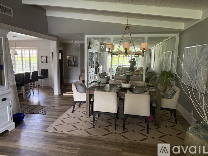 A dining room with a table set for six and a chandelier hanging from the ceiling.
