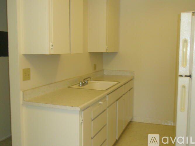 A kitchen with white cabinets and a white fridge.