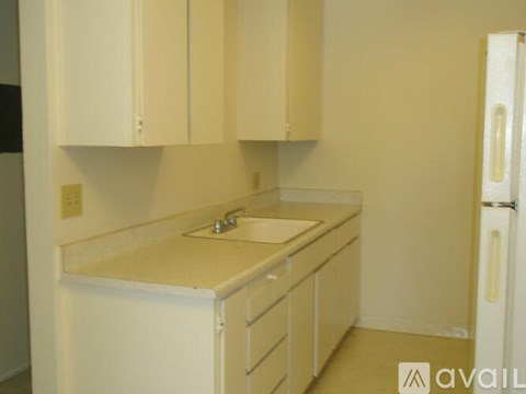 A kitchen with white cabinets and a white fridge.