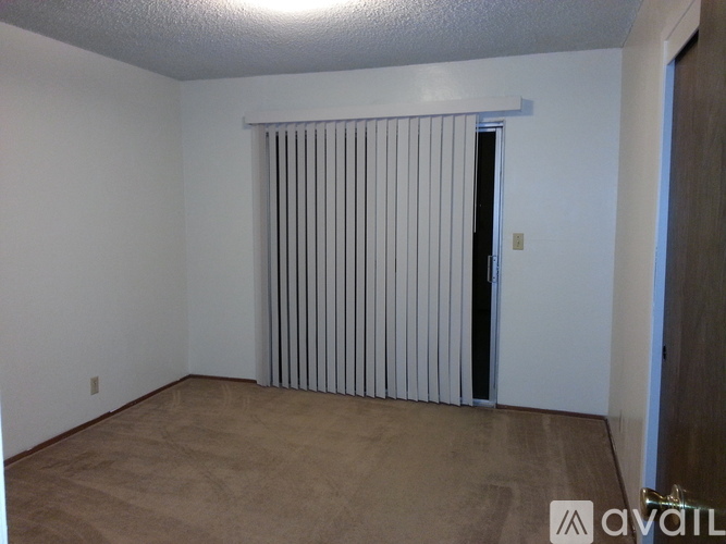 A room with a carpeted floor and a window with blinds.