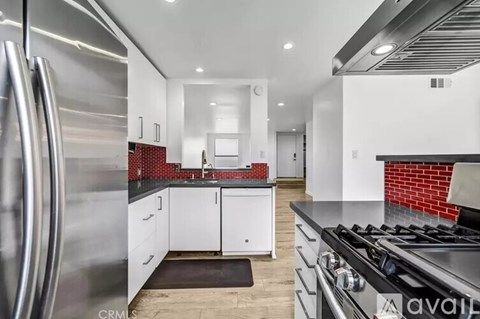 A modern kitchen with a stainless steel refrigerator and a black countertop.