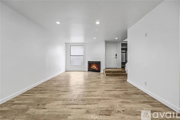 A spacious room with wooden flooring and a fireplace.