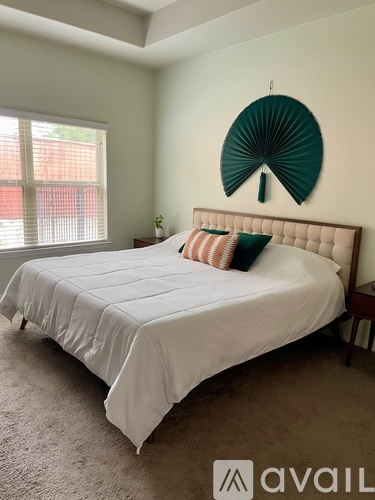 A bedroom with a large bed and a decorative fan on the wall.