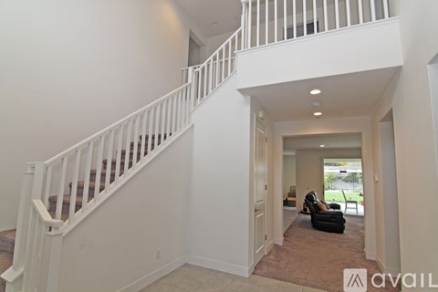 A living room with a couch and a chair is visible from the staircase.