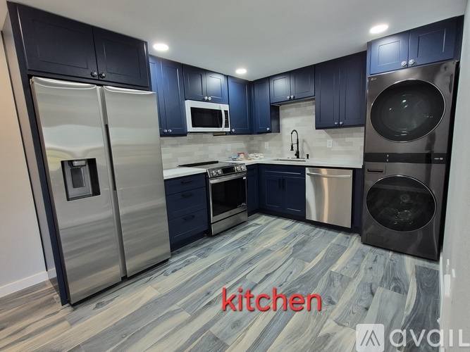 A modern kitchen with dark blue cabinets and stainless steel appliances.
