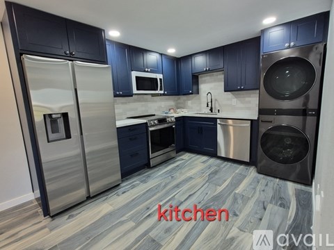 A modern kitchen with dark blue cabinets and stainless steel appliances.