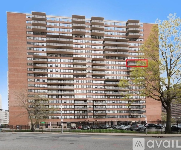A tall apartment building with a parking lot in front.