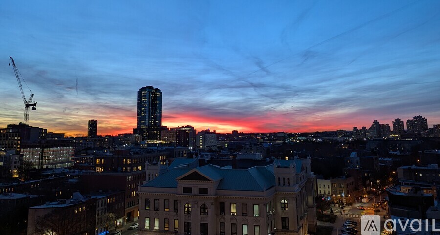 A cityscape at dusk with a tall building in the background.
