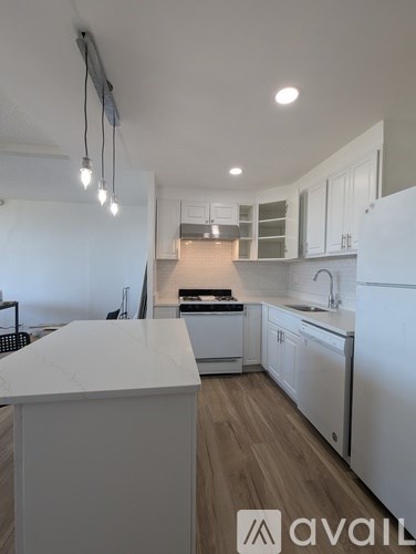 A modern kitchen with white appliances and wooden floors.