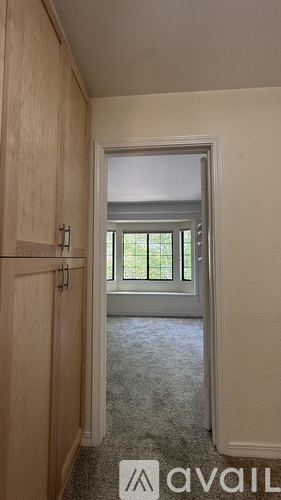 A room with a carpeted floor and a window with a view of trees.