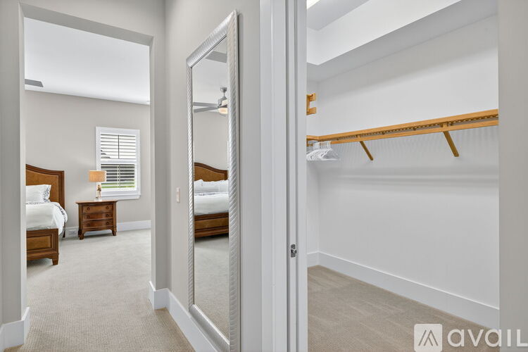 A bedroom with a large mirror and a bed with a wooden headboard.