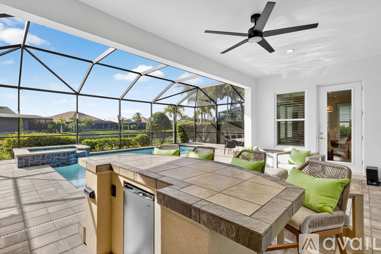 A patio with a table and chairs overlooking a pool.