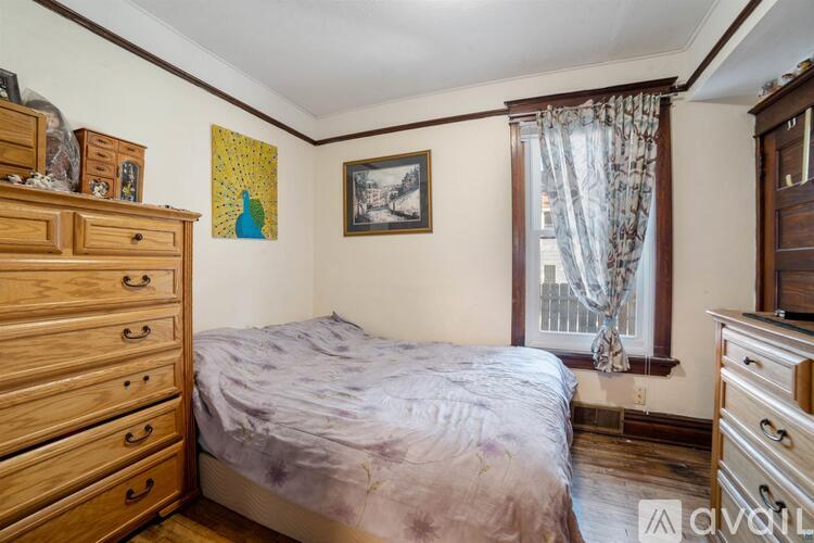 A bedroom with a bed, dresser, and window.