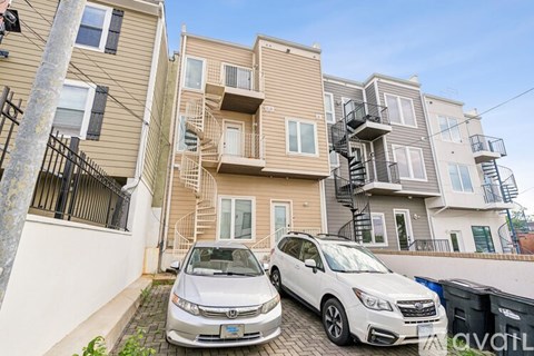 Two cars are parked in front of a two-story apartment building.