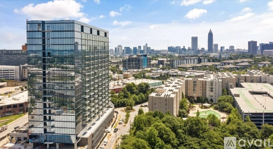 A tall glass building stands in the foreground of a cityscape.
