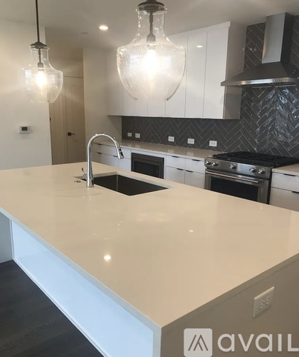 A kitchen with a white countertop and pendant lights.
