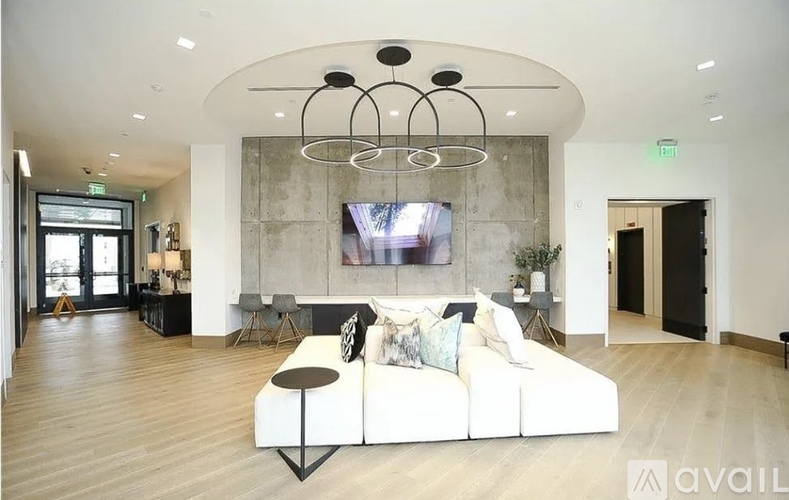 A modern living room with a white sofa and a large TV mounted on the wall.