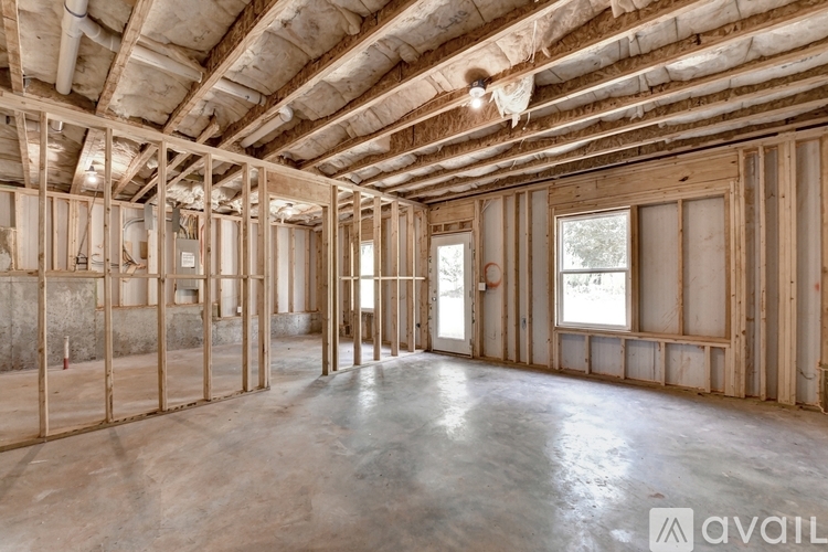 A spacious, unfinished room with wooden framing and a concrete floor.