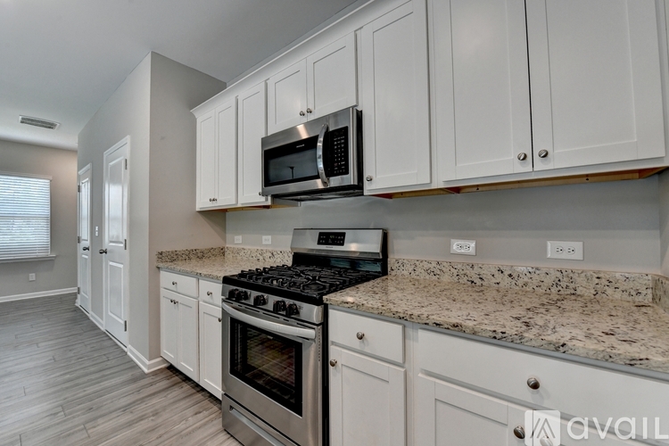 A kitchen with white cabinets and a granite countertop.