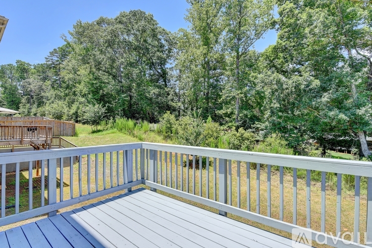 A deck with a railing overlooking a grassy area and trees.