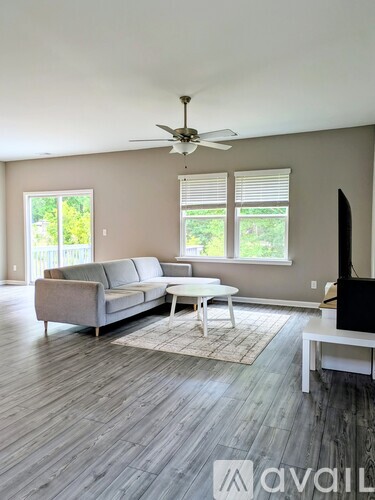 A living room with a grey couch, a white coffee table, and a ceiling fan.