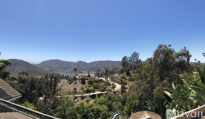 A view from a house overlooking a valley with a lake and mountains in the distance.