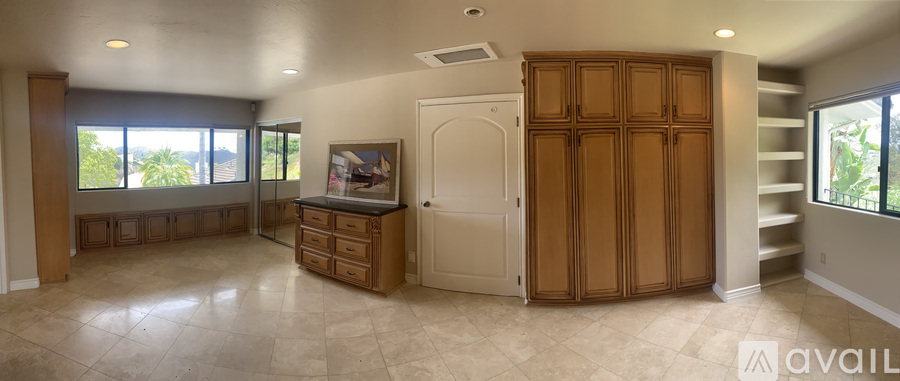A spacious room with a built-in entertainment center and a staircase.