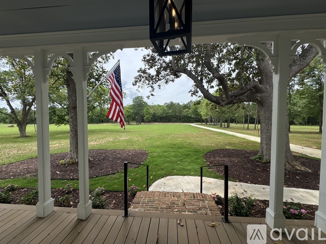 A porch with a flag on a pole and a tree in the background.