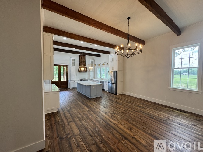 A spacious room with wooden floors and a chandelier hanging from the ceiling.