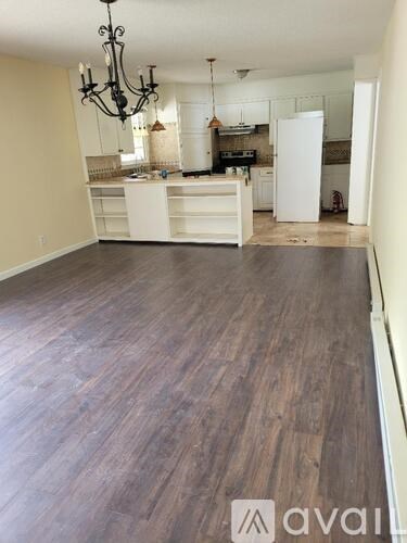 A spacious kitchen with wooden floors and a chandelier.