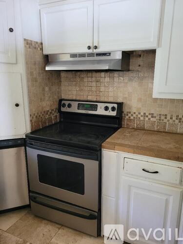 A kitchen with a black oven and white cabinets.