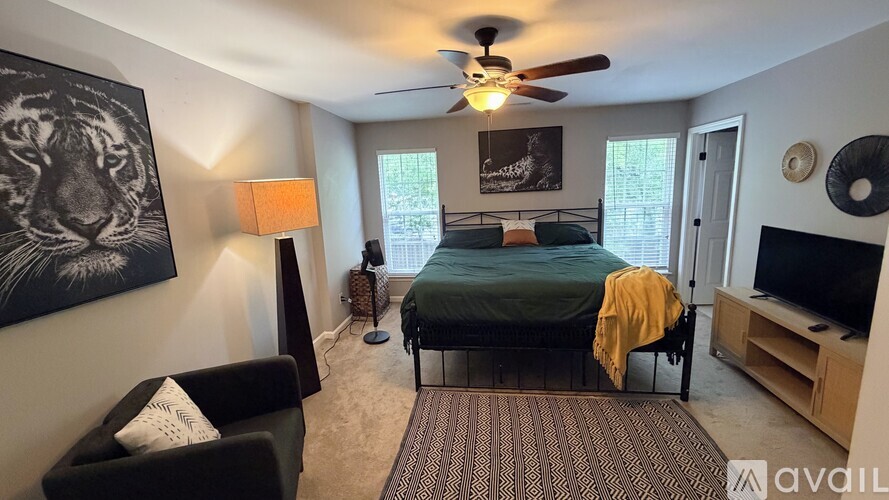 A bedroom with a bed, chair, and a painting of a tiger on the wall.