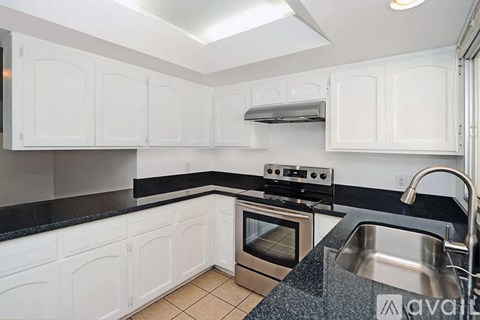 A kitchen with white cabinets and a black countertop.