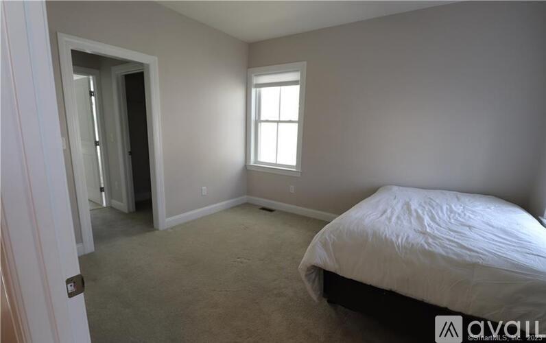 A bedroom with a bed, carpet, and a window.
