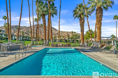 A pool surrounded by palm trees and lounge chairs.