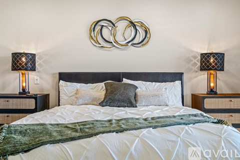 A bedroom with a large bed, a headboard, and two lamps on either side of the bed.